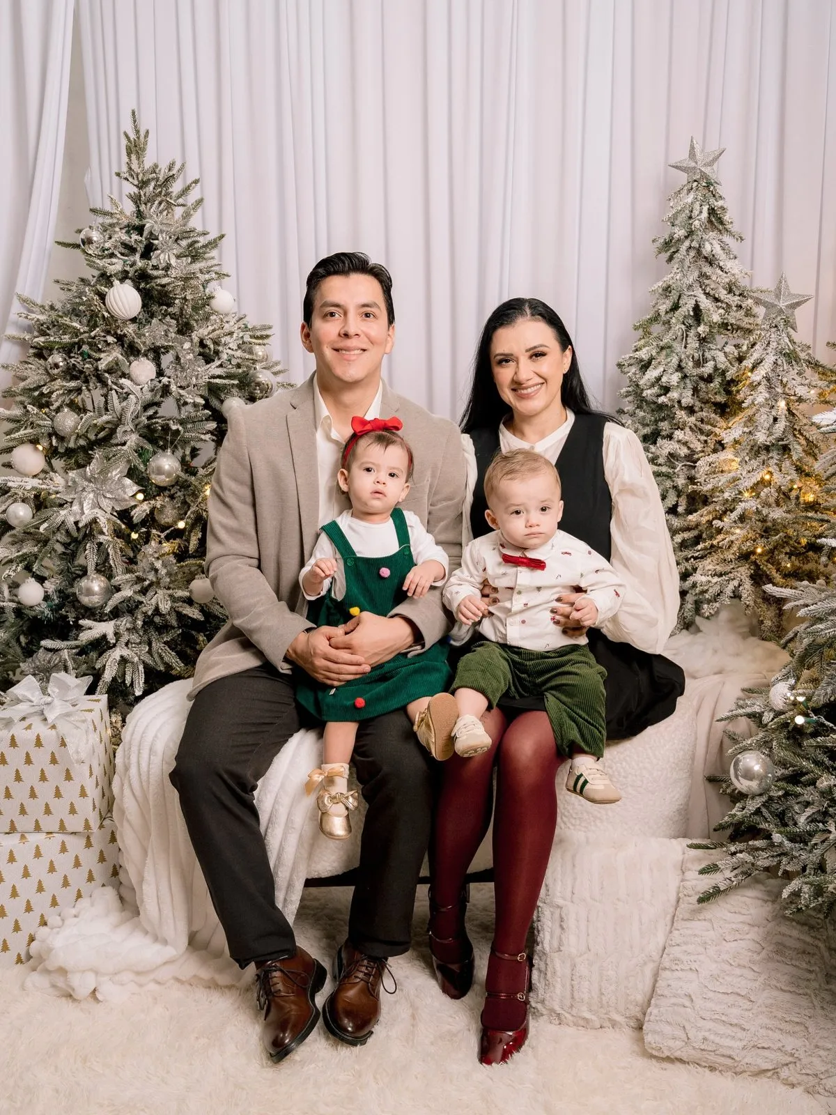 Familia con dos bebés sentada en un sillón entre pinos nevados
