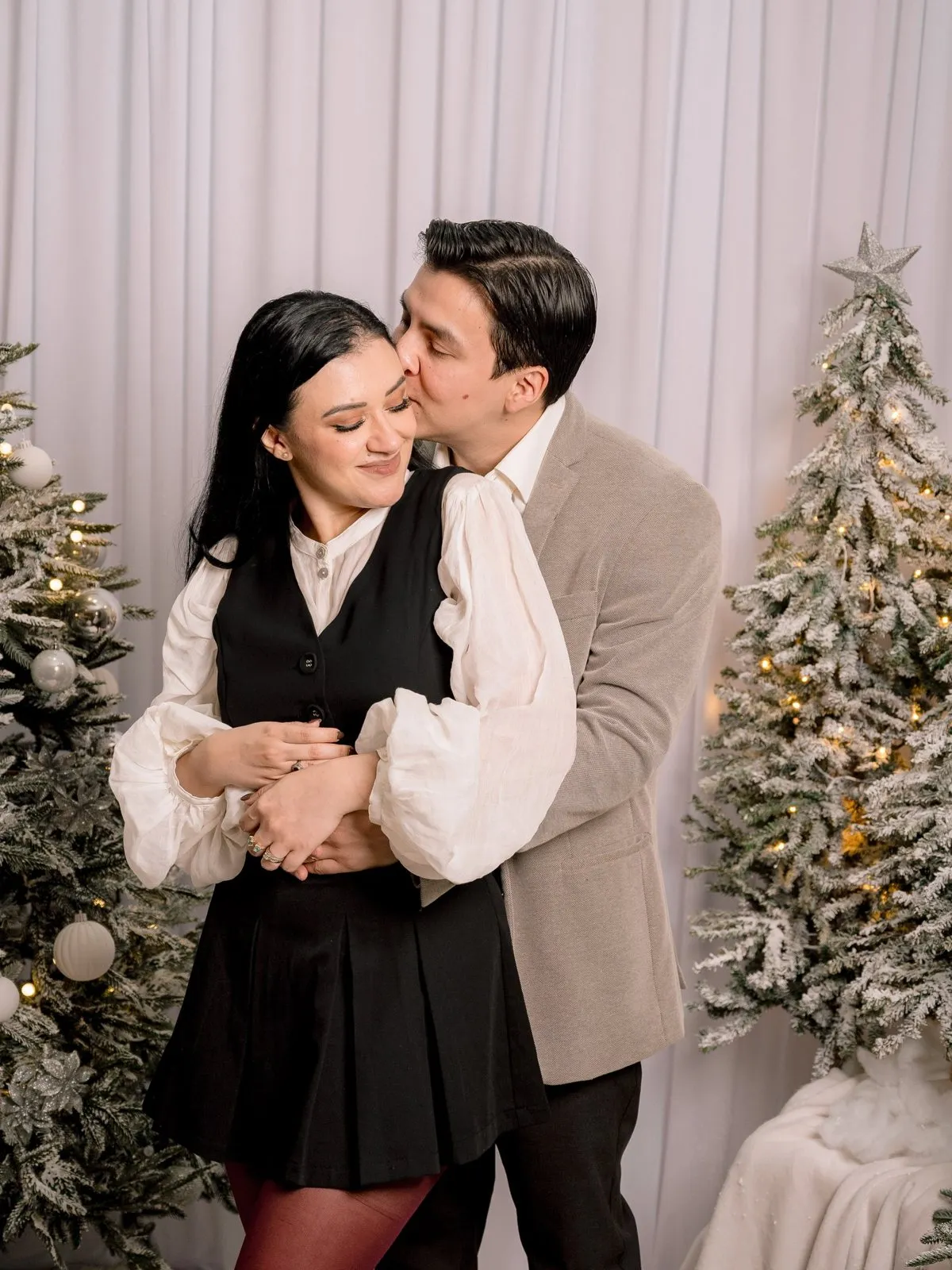 Pareja abrazada entre pinos nevados