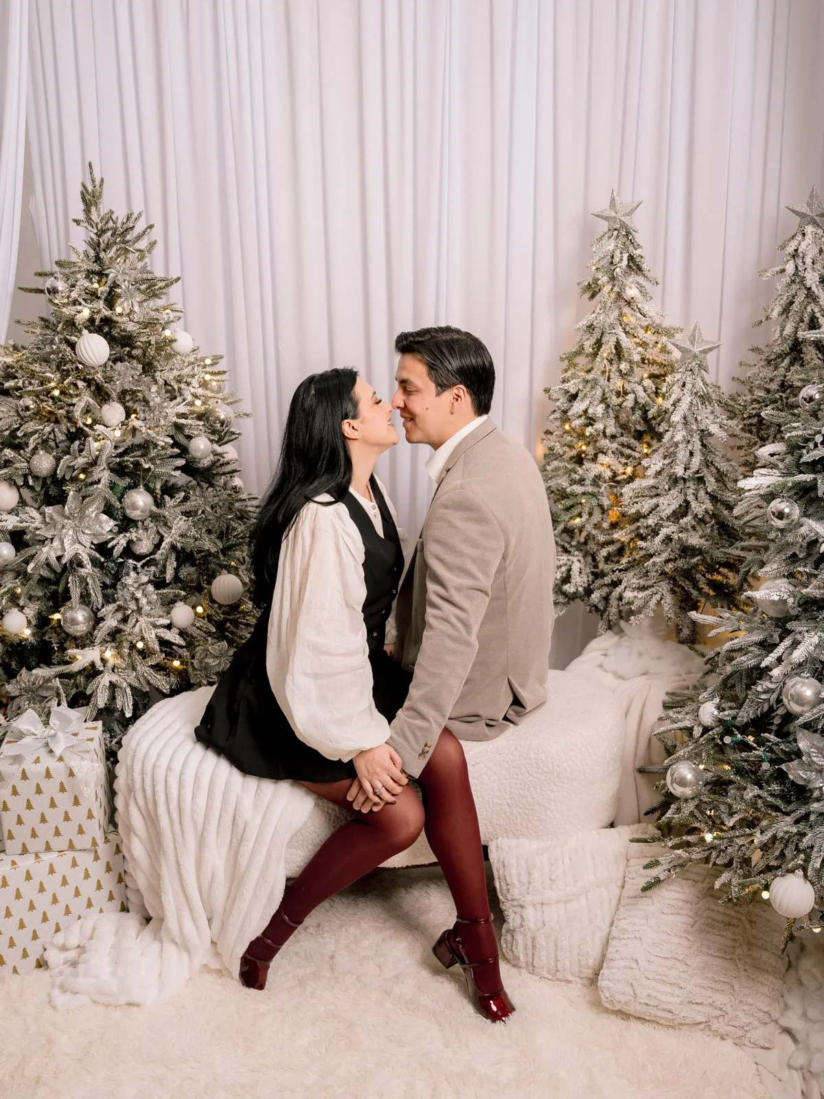 Pareja sentada en un sillón entre pinos nevados